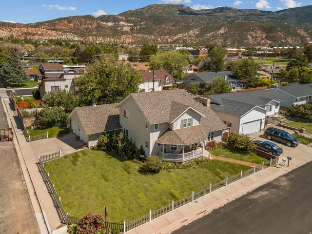 Two-story residence featuring a covered front porch, an attached two-car garage, and a fenced front yard with a paved driveway