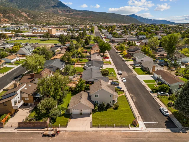 Paved residential street with sidewalks, surrounded by established homes featuring pitched roofs and green lawns