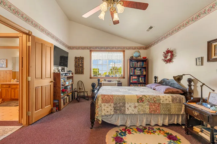 Vaulted ceiling with a ceiling fan, wood-frame window, and a built-in bookshelf