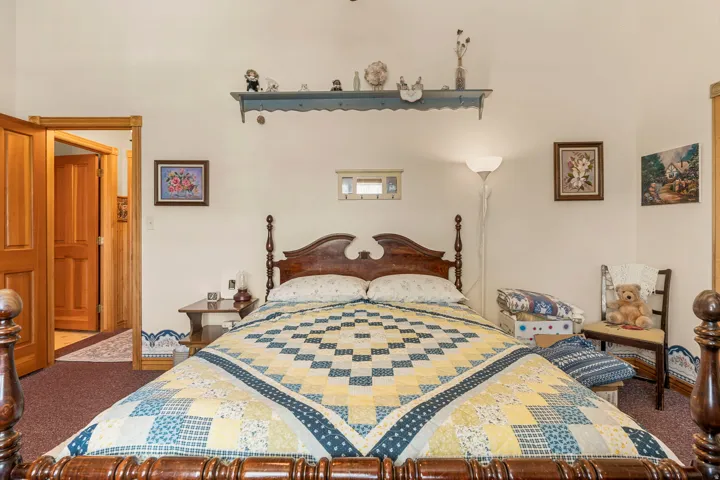 Hardwood bed frame with turned posts, light-toned walls, wood-finish doors, and a small transom window