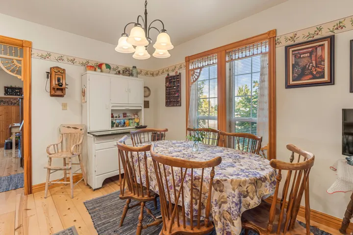 Hardwood flooring, painted walls, two large windows, built-in cabinetry, and a five-light chandelier