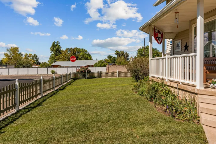 Front yard featuring a manicured lawn, picket fencing, and mature landscaping