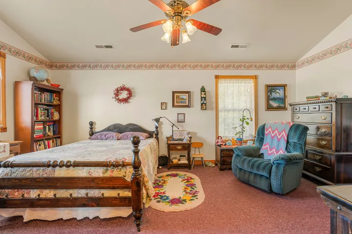 Vaulted ceiling with a ceiling fan, wall-to-wall carpeting, and wood-framed windows