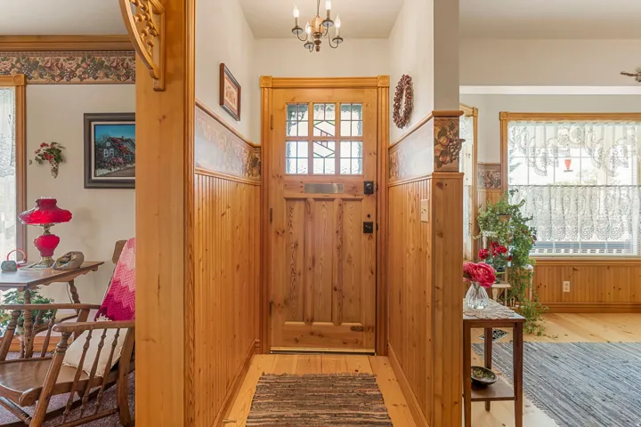 Wood-finish flooring, beadboard paneling, and a wood entry door with leaded glass