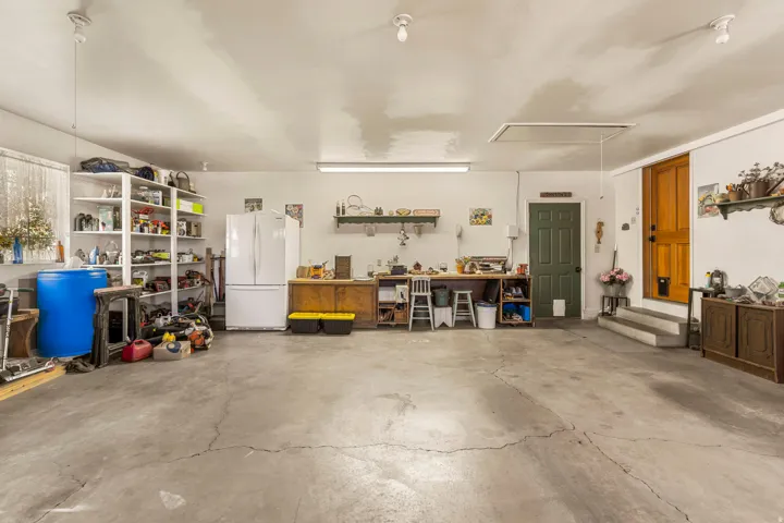 Concrete flooring, built-in shelving, two entry doors, and a ceiling-mounted access panel
