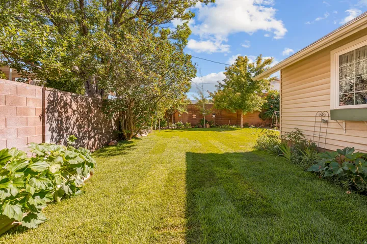 Expansive backyard featuring a manicured lawn, established landscaping, privacy fencing, mature trees, and a siding exterior