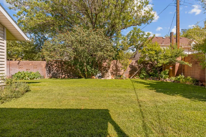 Expansive lawn area with mature trees and a brick privacy wall
