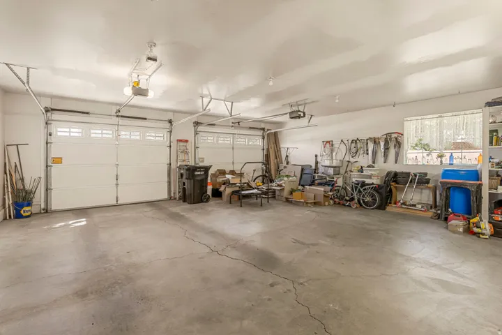 Two overhead garage doors with window panels, concrete flooring, overhead lighting, and a single window
