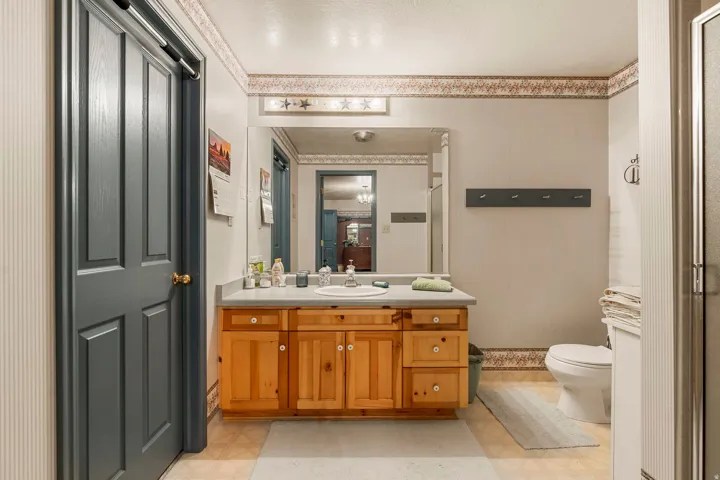 Bathroom featuring a single vanity with wood cabinetry, a large wall-mounted mirror, and an integrated sink