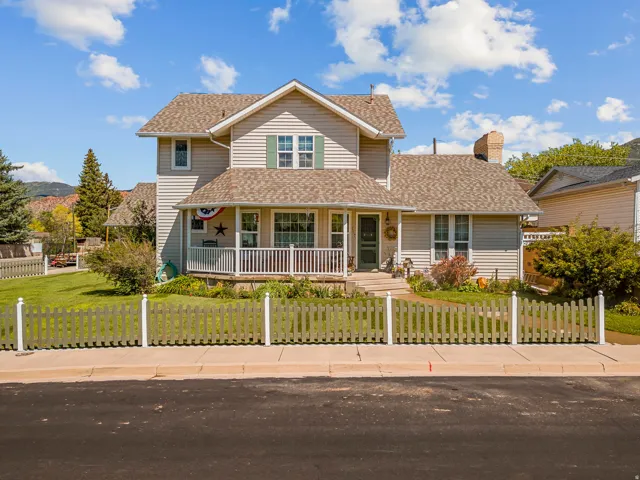 Two-story residence featuring light-colored siding, a covered porch with white railings, and a peaked roof
