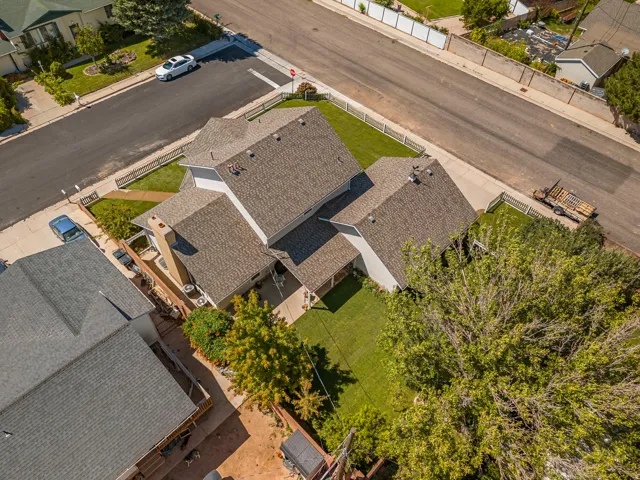 Multi-level roofing with visible shingles, surrounded by a manicured lawn and mature landscaping