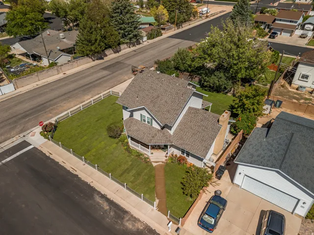 Two-story residence with a covered porch, an attached two-car garage, a separate single-car garage, a fenced front yard, and a paved driveway