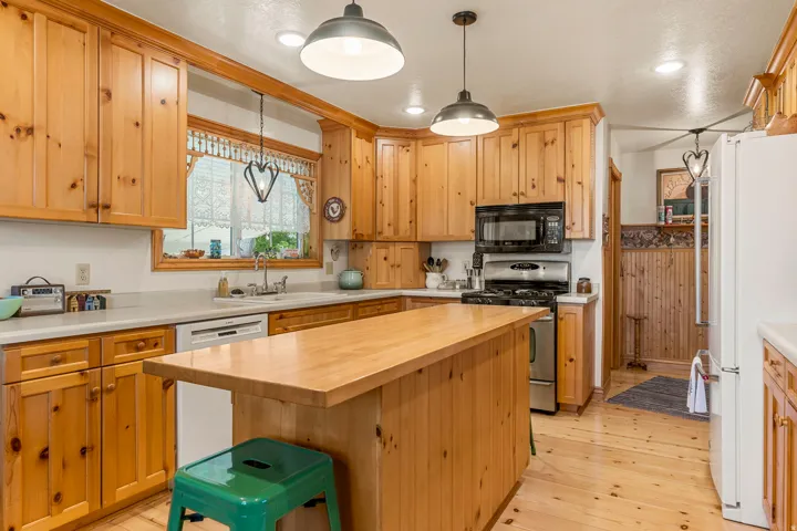Wood-finish cabinetry, wood-finish flooring, butcher block island, stainless steel range, and built-in microwave