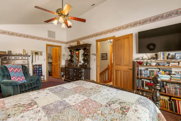 Vaulted ceiling with an attached ceiling fan, two solid wood doors, and wood-finish flooring