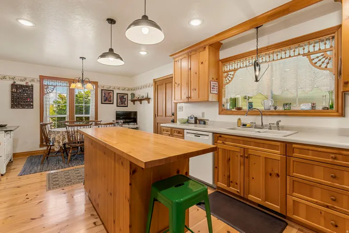 Kitchen featuring wood-finish flooring, wood cabinetry, built-in dishwasher, and a center island with a wood countertop