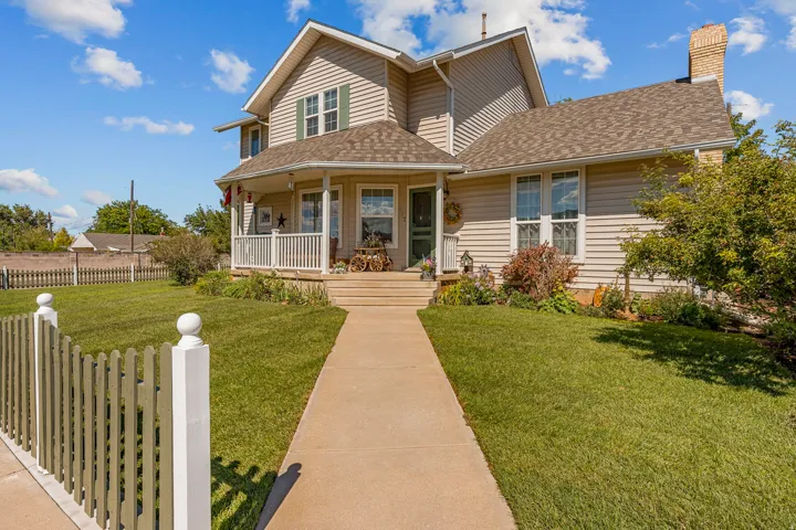 Traditional siding exterior with an inviting covered porch, a concrete walkway, and a picket fence
