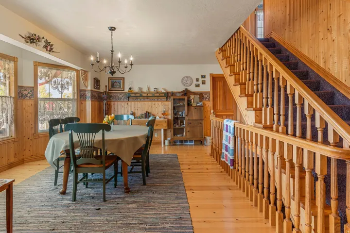 Hardwood flooring, wood paneling, wood-framed windows, and a hardwood staircase with carpeted treads