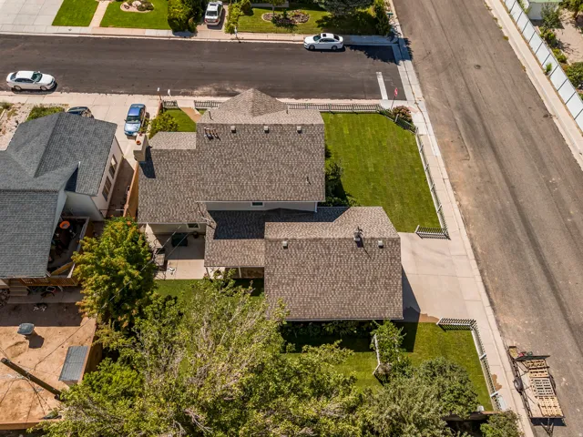 Shingle roofing with multiple gables, extensive paved driveway, and manicured front lawn
