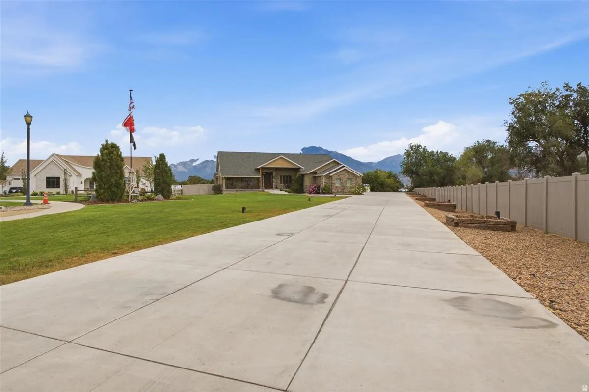Concrete driveway with flanking landscape beds, leading to a stone and siding exterior