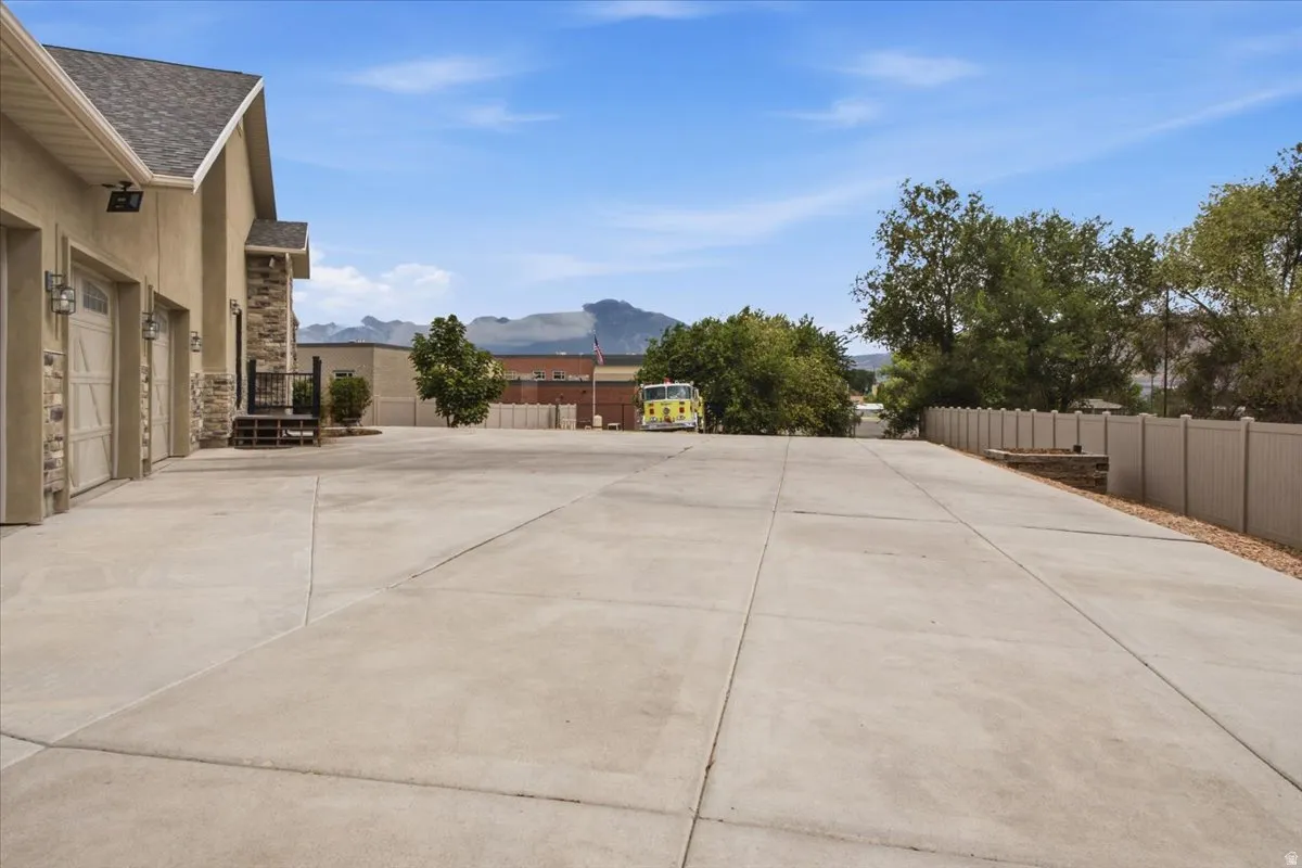Expansive concrete driveway with a three-car garage featuring individual doors and exterior lighting