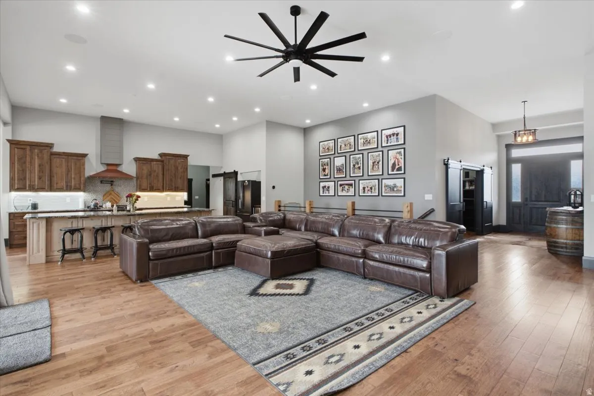 Spacious open-concept living area featuring wood-finish flooring, recessed lighting, and a large ceiling fan