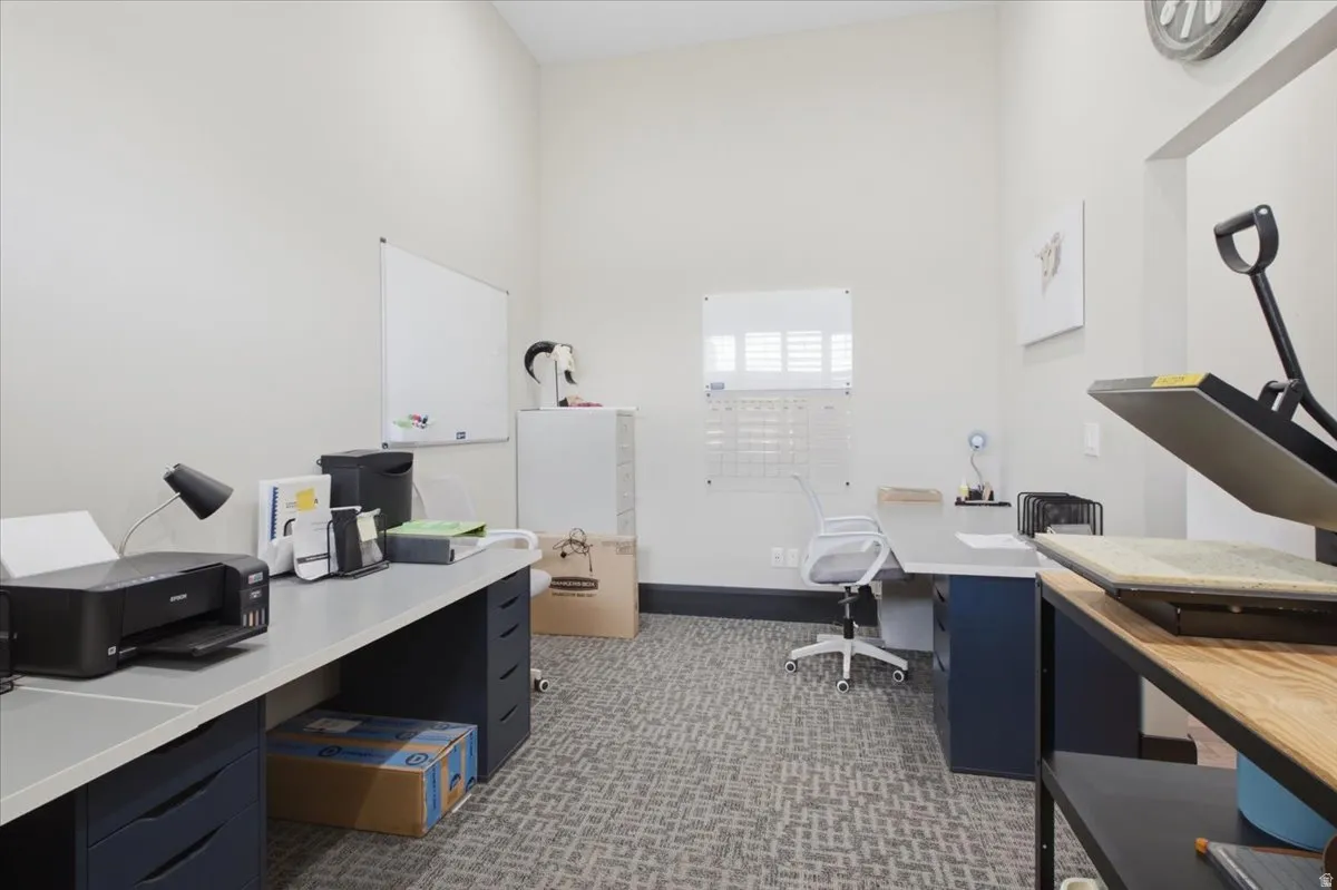Recessed office space featuring patterned carpet, light-toned walls, and a high ceiling