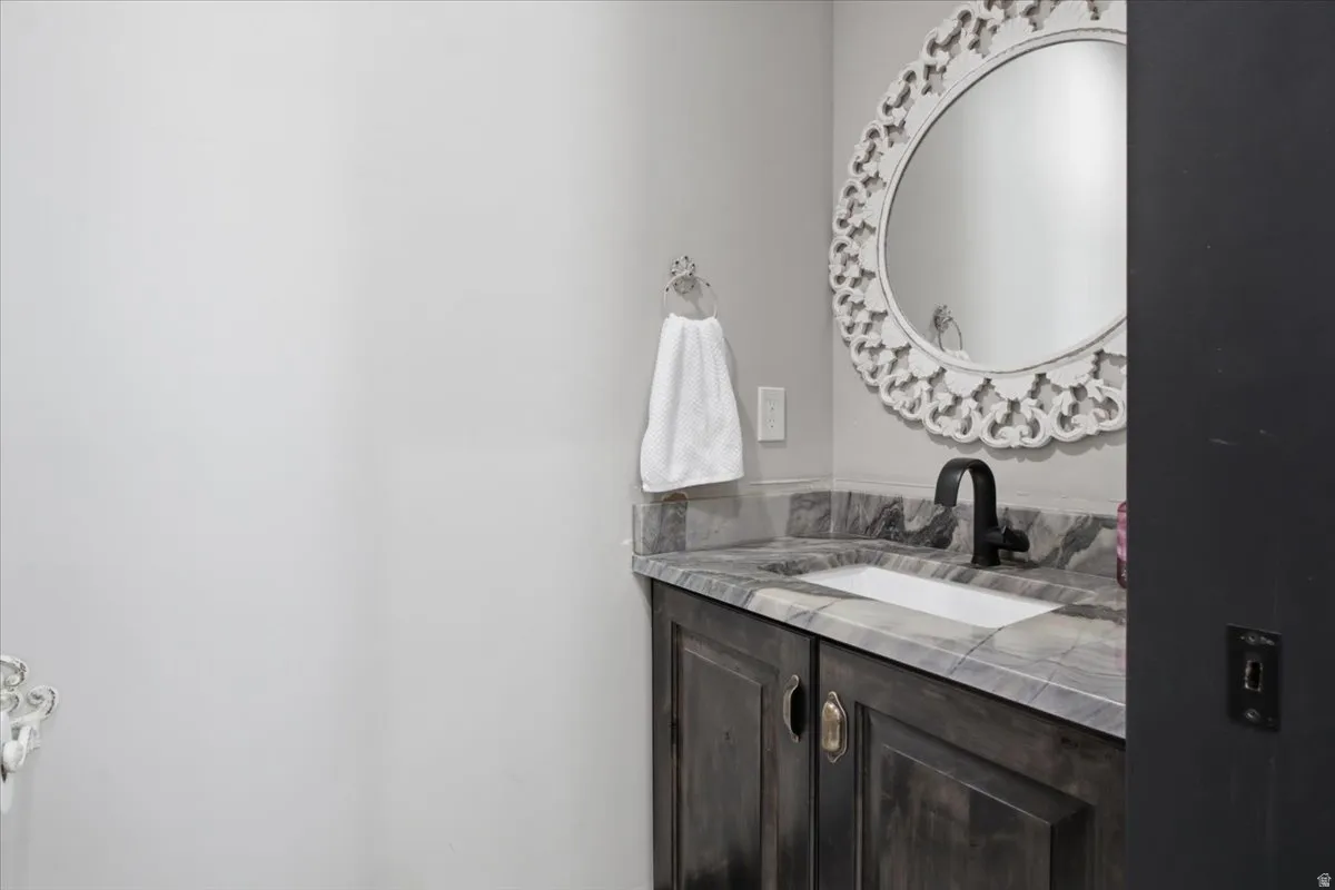 Vanity with stone countertop, integrated sink, and dark wood-finish cabinetry