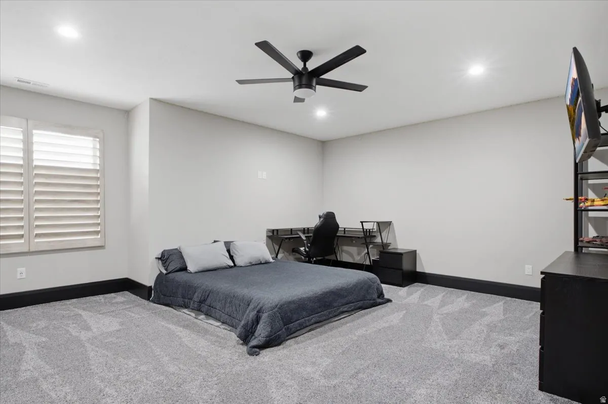 Plush carpeting, recessed lighting, and a contemporary ceiling fan