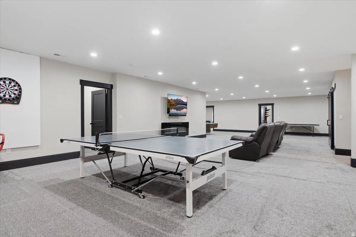 Spacious recreation area featuring recessed lighting, a built-in fireplace, and dark trim