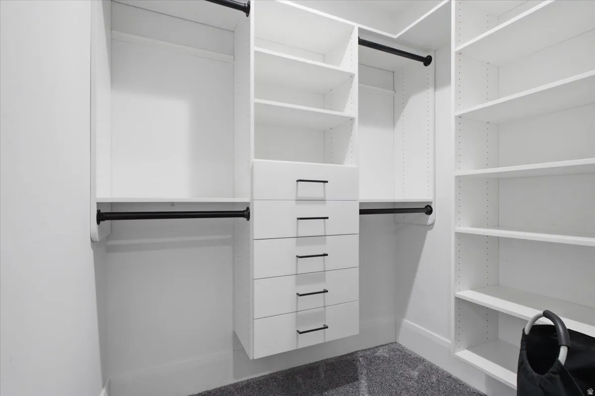 Built-in closet system featuring white shelving, integrated drawers with black hardware, and black hanging rods