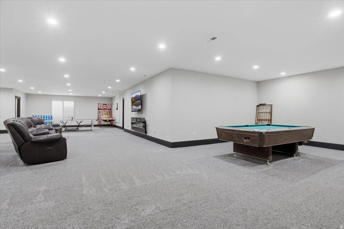 Spacious entertainment area with recessed lighting, carpet flooring, and window blinds