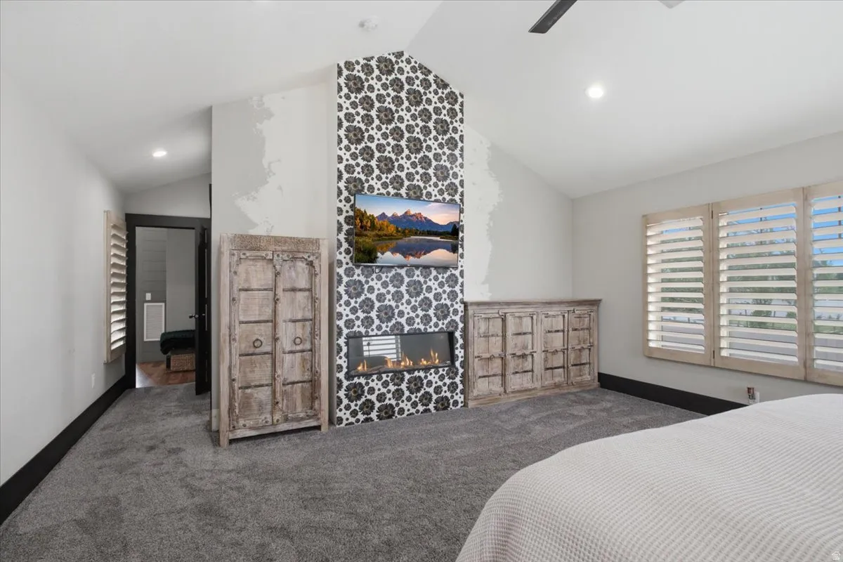 Vaulted ceiling featuring a ceiling fan, recessed lighting, and a tiled fireplace surround