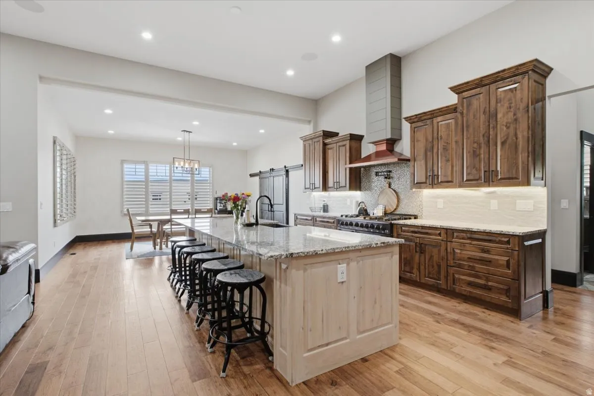 Spacious kitchen with a large central island, granite countertops, wood-finish flooring, dark wood cabinetry, and a sliding barn door