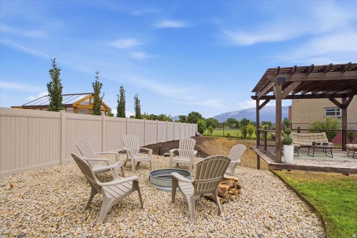 Expansive backyard featuring a gravel fire pit area, a multi-level deck with a wood pergola, and a private vinyl fence