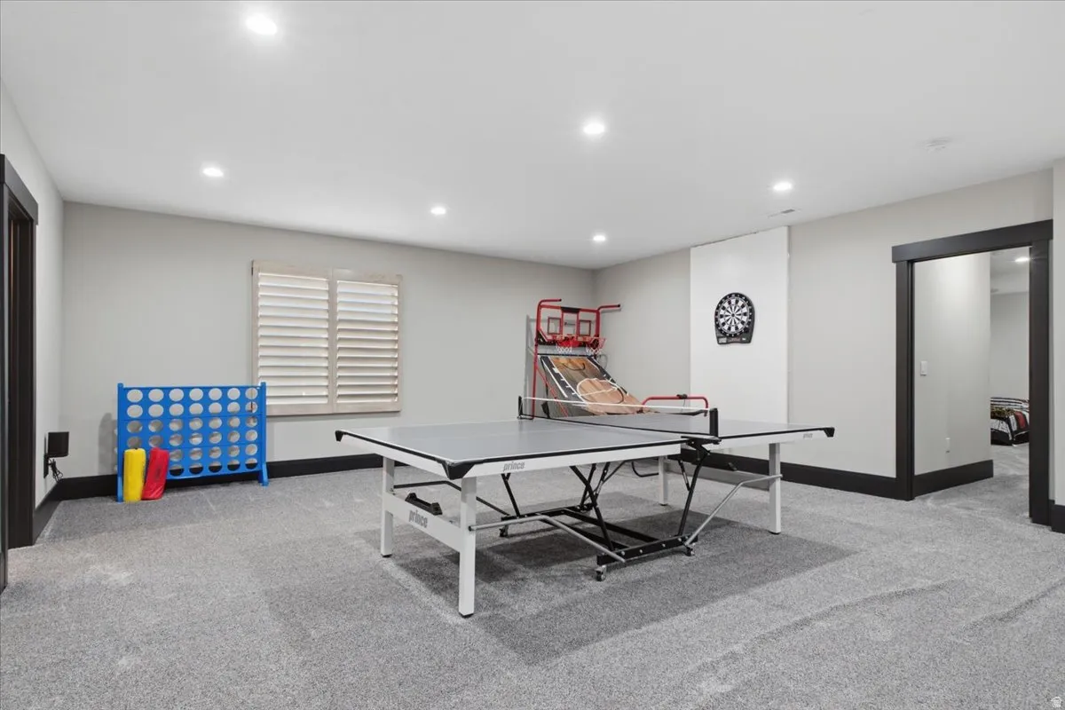 Expansive recreation room featuring recessed lighting, a window with plantation shutters, and dark trim details