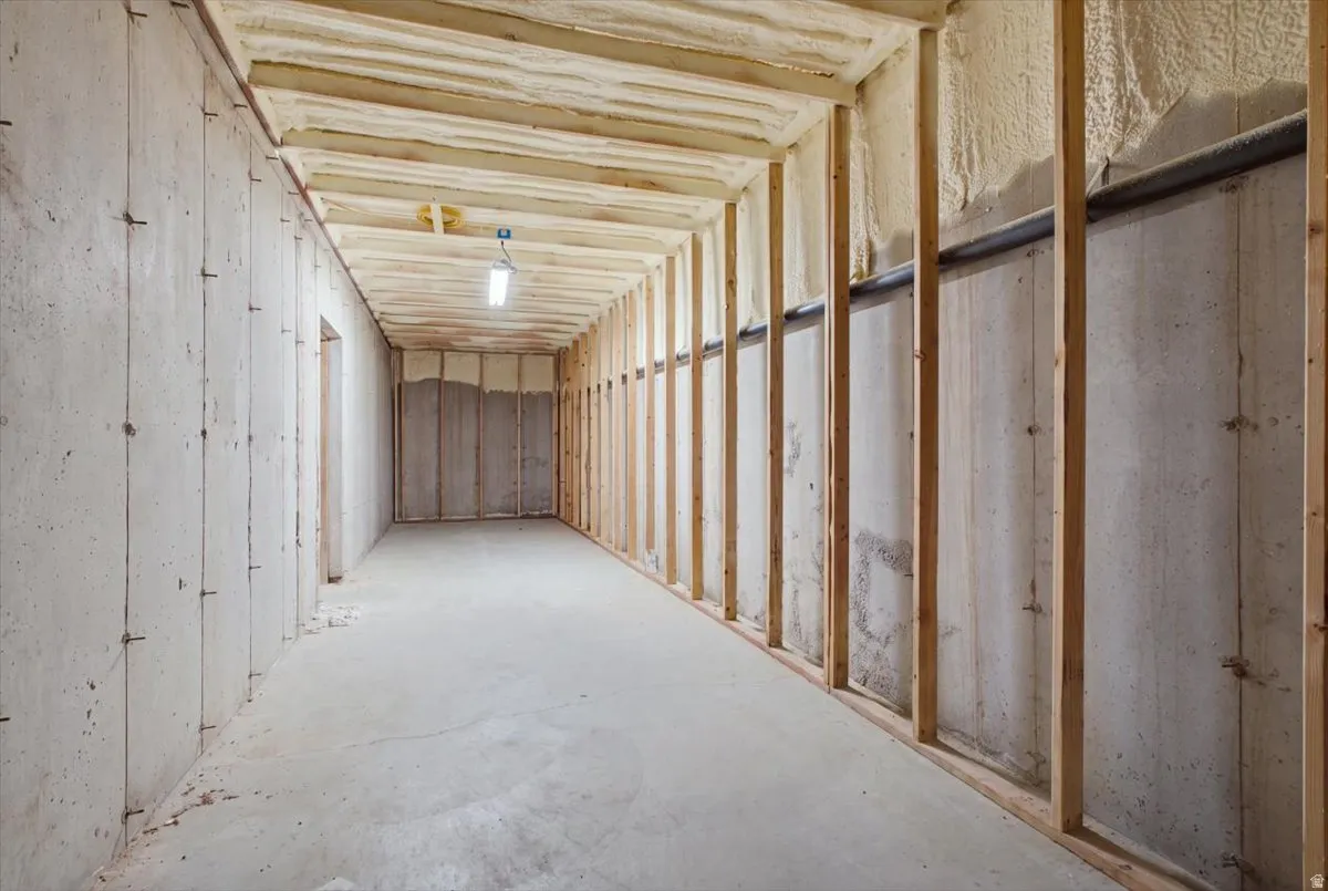 Unfinished basement with concrete flooring and exposed wood framing