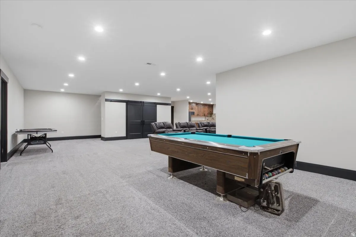 Expansive carpeted area featuring recessed lighting, dark trim, and dual dark barn doors