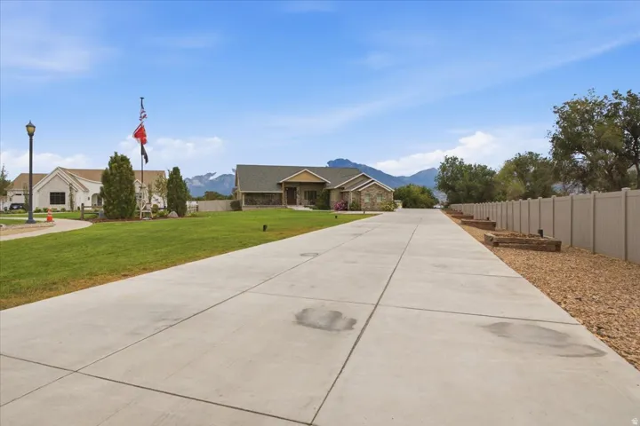 Concrete driveway with flanking landscape beds, leading to a stone and siding exterior