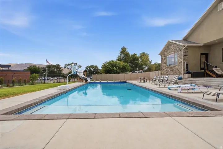 Outdoor swimming pool with concrete surround, adjacent lawn area, and stone-accented exterior