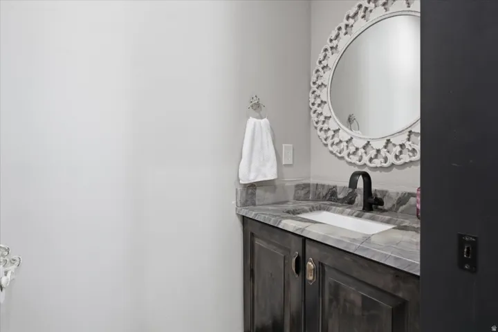 Vanity with stone countertop, integrated sink, and dark wood-finish cabinetry