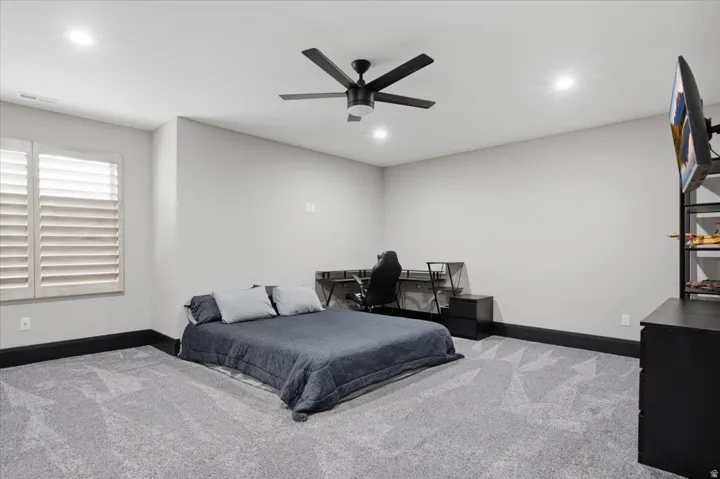Plush carpeting, recessed lighting, and a contemporary ceiling fan