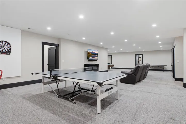 Spacious recreation area featuring recessed lighting, a built-in fireplace, and dark trim