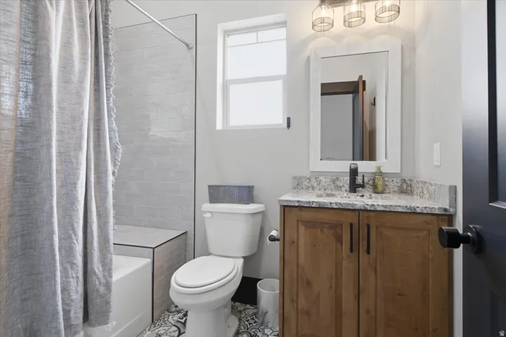 Wood-finish vanity with a stone-finish countertop, undermount sink, and matte black faucet