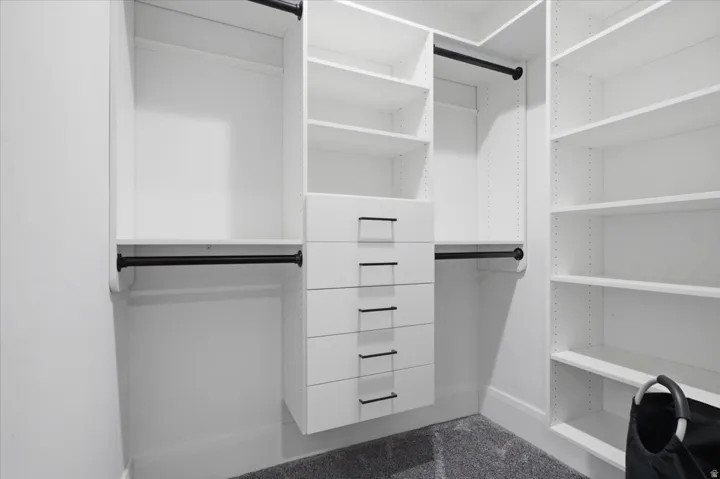 Built-in closet system featuring white shelving, integrated drawers with black hardware, and black hanging rods