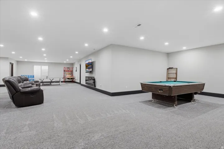 Spacious entertainment area with recessed lighting, carpet flooring, and window blinds