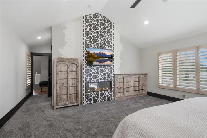 Vaulted ceiling featuring a ceiling fan, recessed lighting, and a tiled fireplace surround