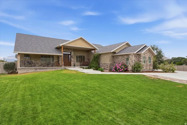 Stone and stucco exterior, covered front porch, dark wood-finish front door, ample front yard, and a paved driveway