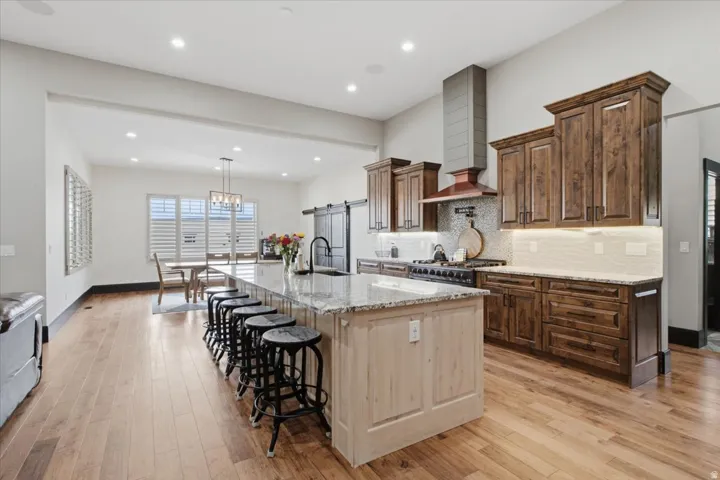 Spacious kitchen with a large central island, granite countertops, wood-finish flooring, dark wood cabinetry, and a sliding barn door
