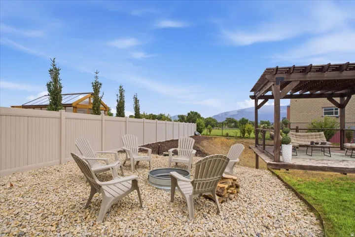 Expansive backyard featuring a gravel fire pit area, a multi-level deck with a wood pergola, and a private vinyl fence