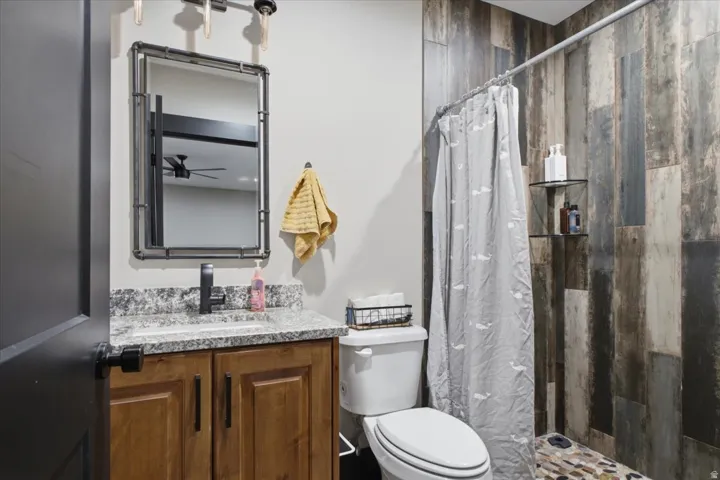 Vanity with a granite countertop, undermount sink, and dark wood-finish cabinetry